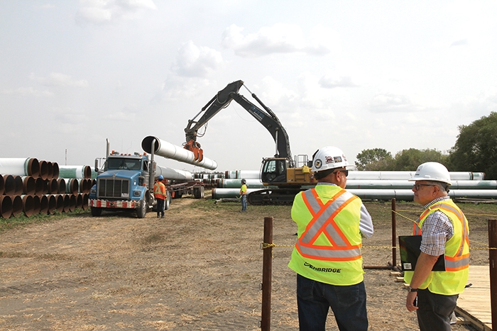 Al Sawatzky, Construction Manager, Line 3 Replacement Program with Enbridge Pipelines, left, and federal Minister of Public Safety Ralph Goodale watch as pipe is loaded up for the Enbridge Line 3 replacement. The town and RM of Moosomin are trying to revive consideration of another pipeline project--Energy East.
