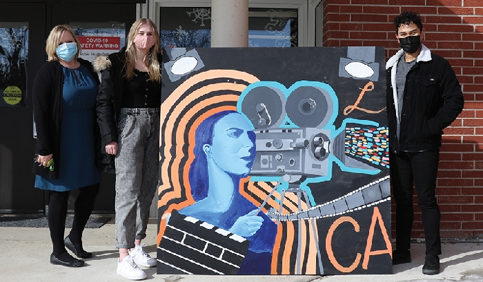 Vice Principal of McNaughton High School Sherrie Meredith poses with former students Kadence Meredith (left) and Primo Oroyo (right) and a segment of their soon-to-be completed mural.