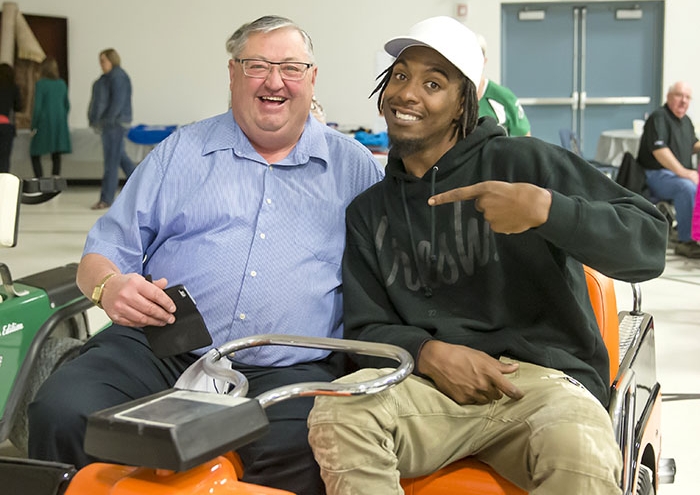 <b>Successful fundraiser</b> Moosomin Mayor Larry Tomlinson and Rider Duron Carter at the Sportsmans Dinner in Moosomin April 28. The dinner was part of a weekend full of events that raised $75,000 for the new clubhouse at Pipestone Hills Golf Club. Tomlinson and Carter are sitting on one of two custom golf carts created for the auction that night one with a Harley theme and one with a Rider theme.