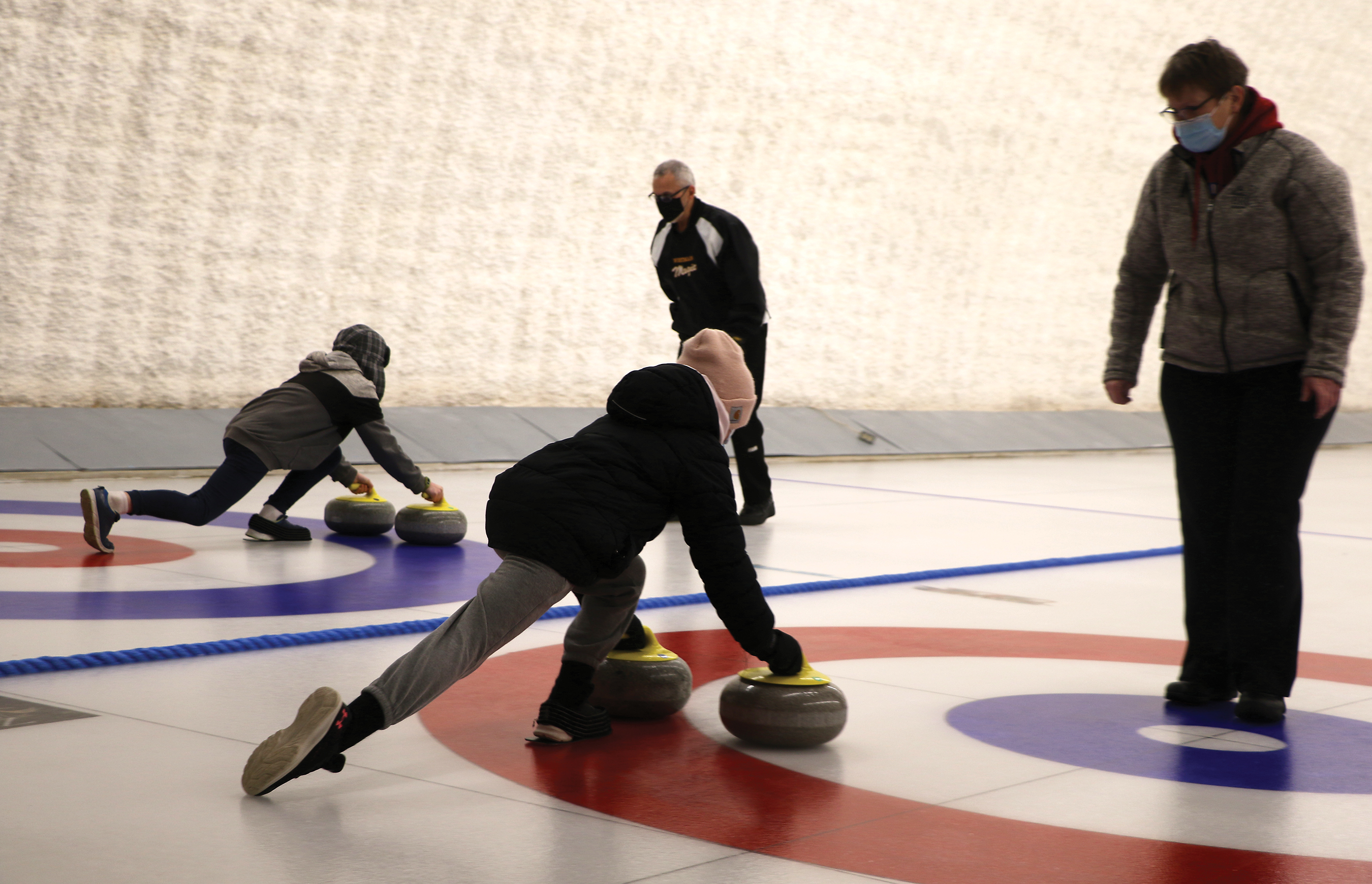 Students from Maryfield School learning how to slide with curling rocks on the ice with curling instructors Randy O’Greysik (left) and Barb Swallow.