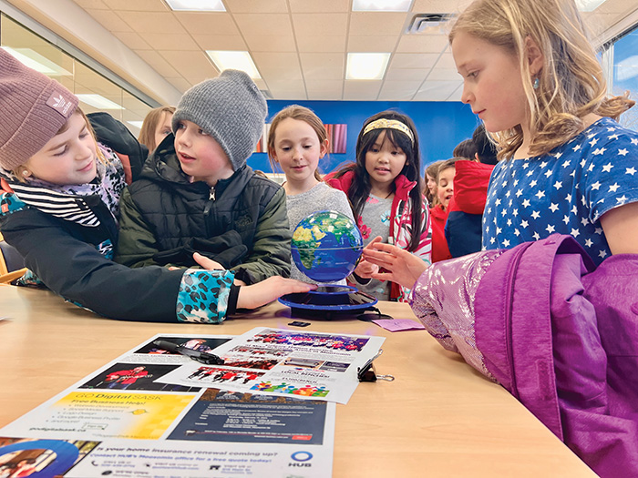 Students checking out a floating globe on Kevin Weedmarks desk.<br />
