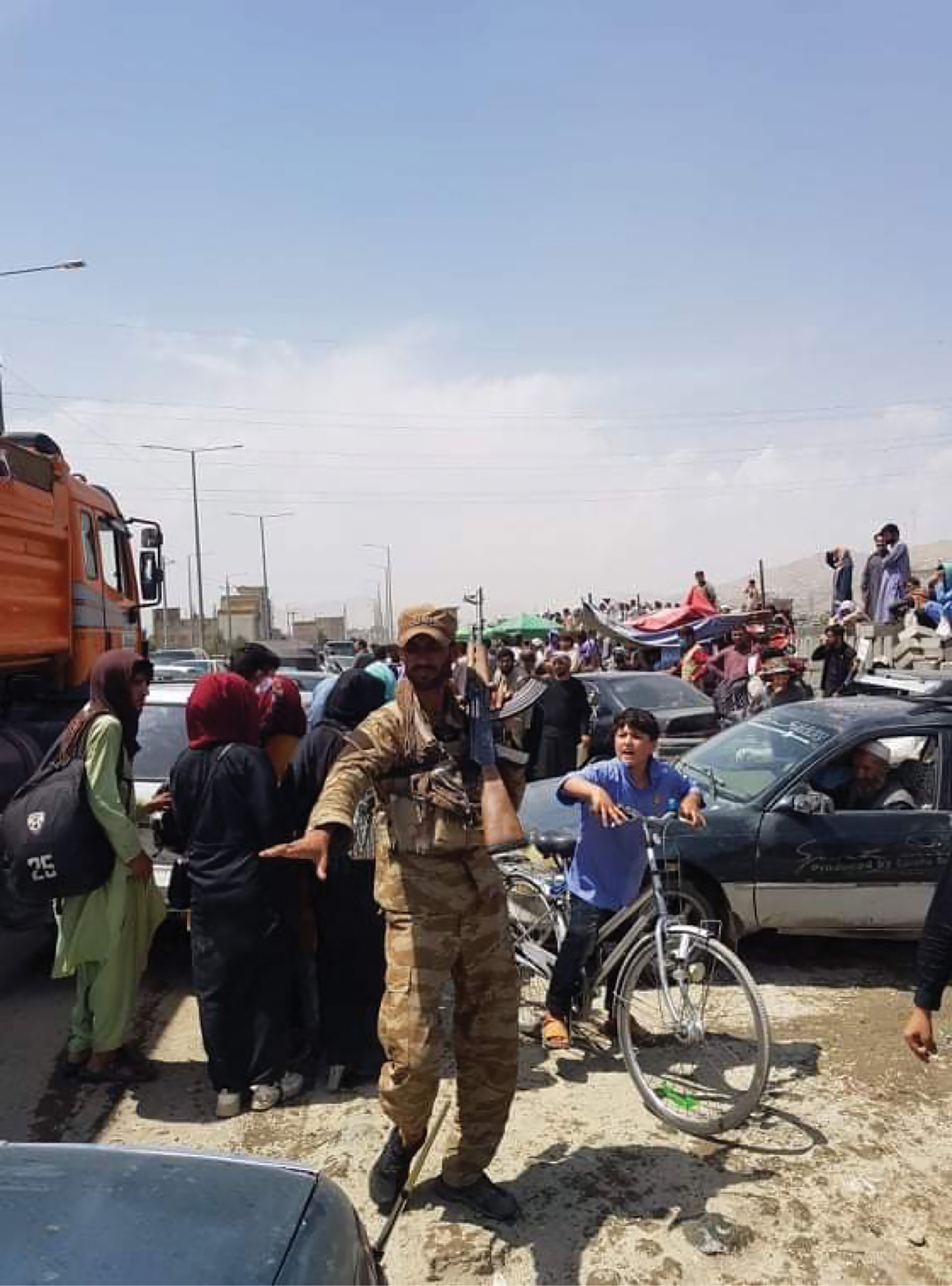 Man standing in a crowd of people and vehicles.