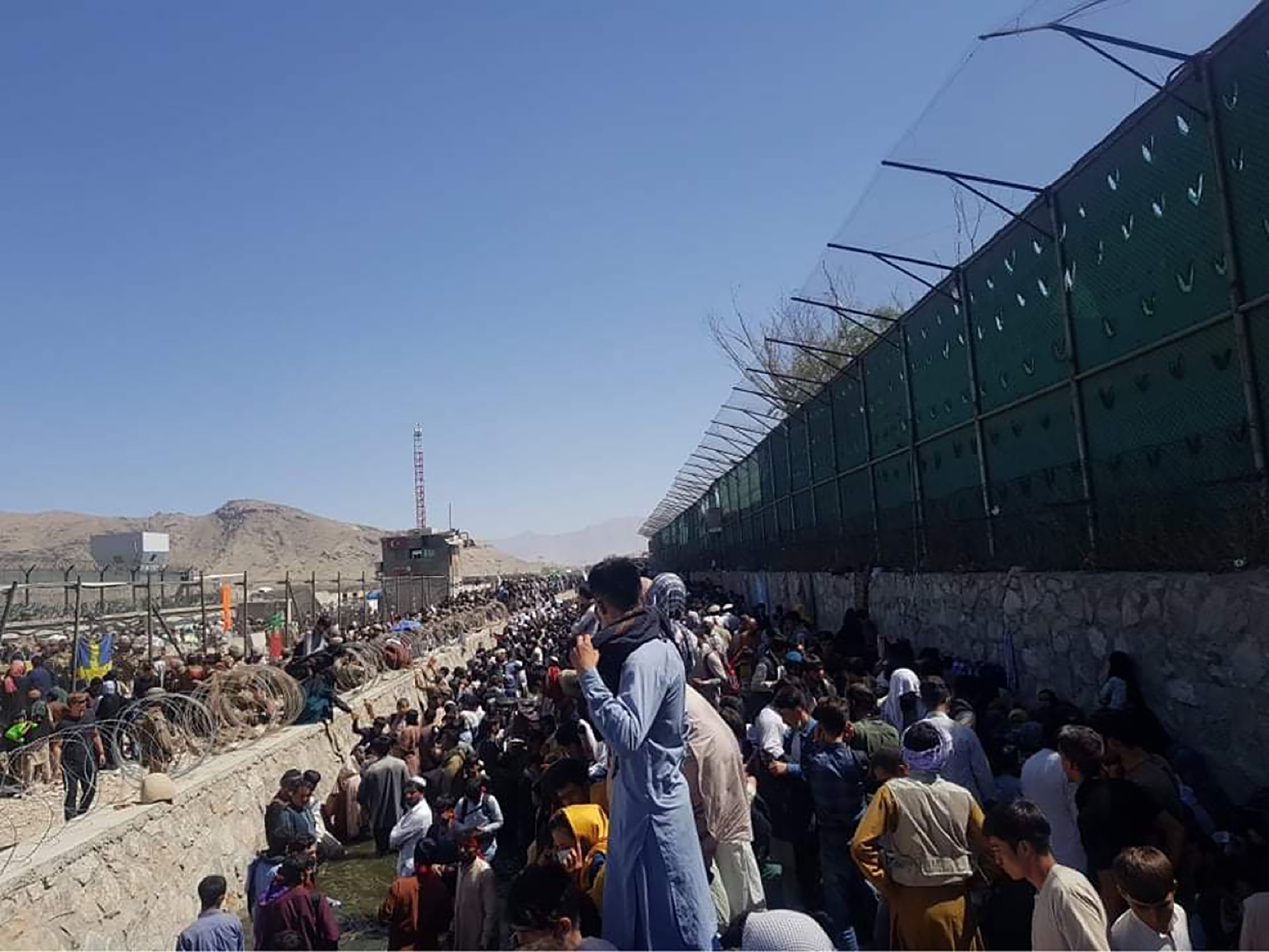 Groups of people gathered on the ground outside of airport.