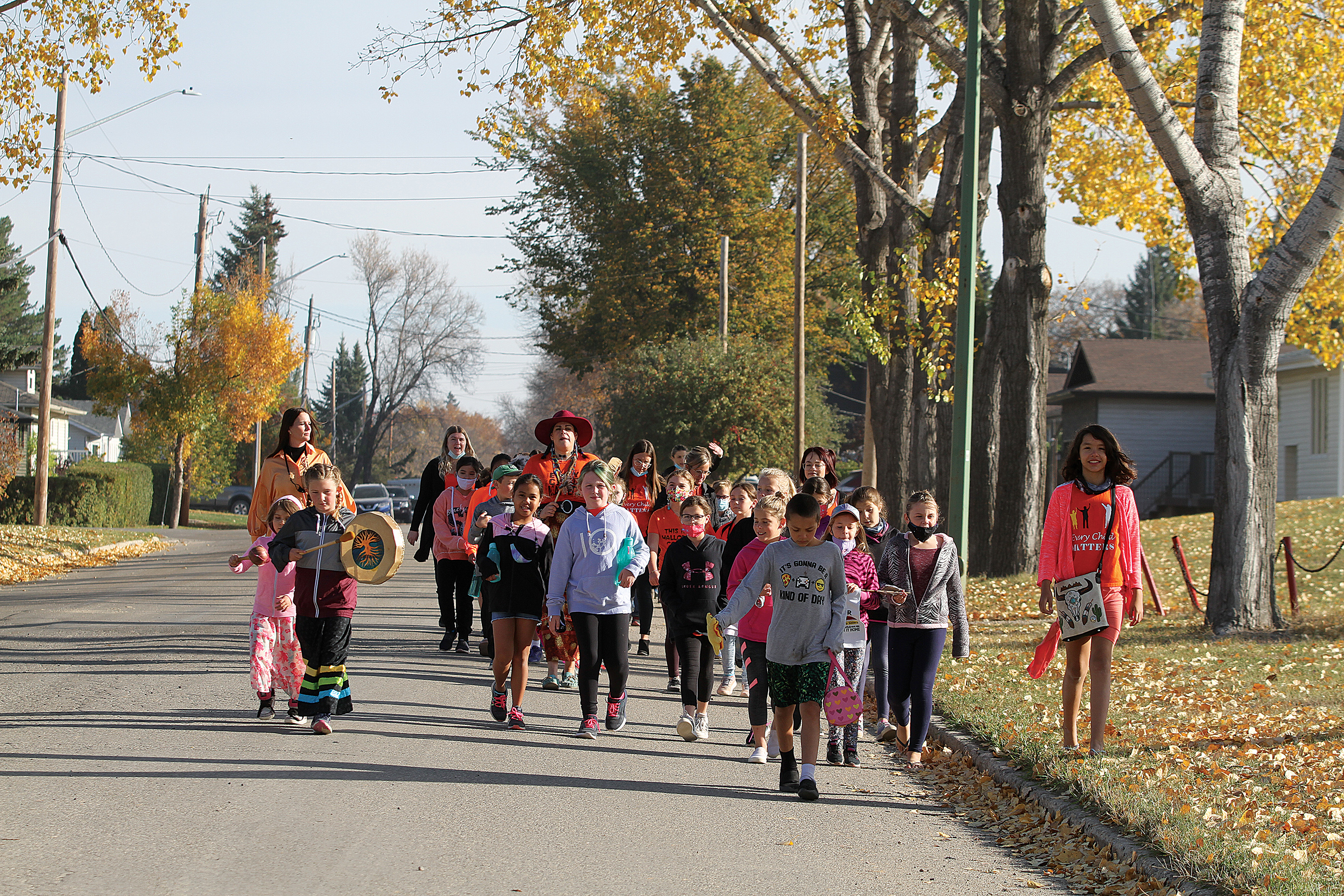 The students walking to the labyrinth from the school while drumming.