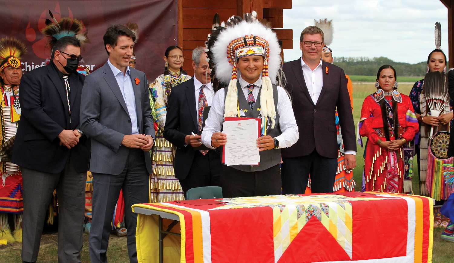 Cowessess First Nation Chief Cadmus Delorme with Prime Minister Justin Trudeau and Premier Scott Moe holding the newly signed agreement.