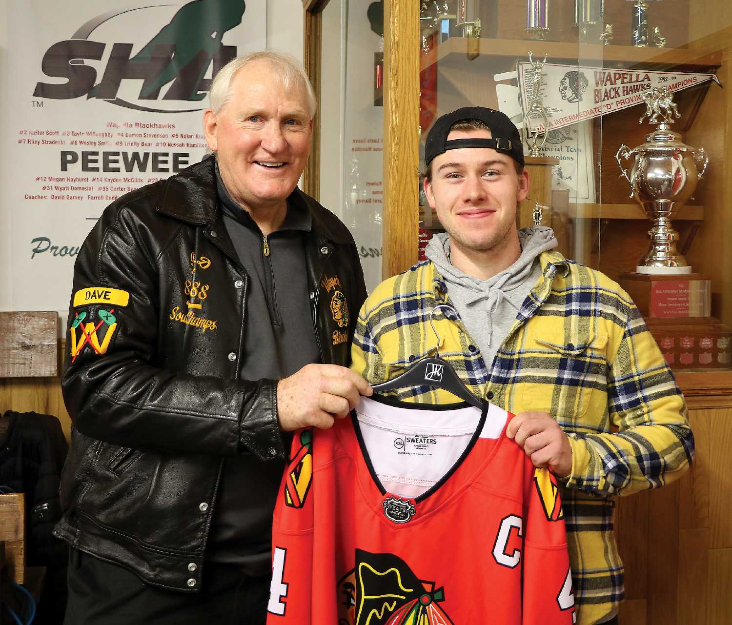 Moosomin Senior Rangers player Jevon Schwean presenting the Dunn Blackhawks jersey to Dave Dunn during the jersey auction after the game. Dunn bid $2,500 to take home his jersey that night.