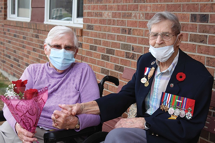 Louise, the wife of Les Downing. Louise is a resident in a local seniors home and her husband came to visit her after his 100th birthday parade, bringing her a bouquet of red roses, her favorite flowers. Later the two had a video call with their family members.