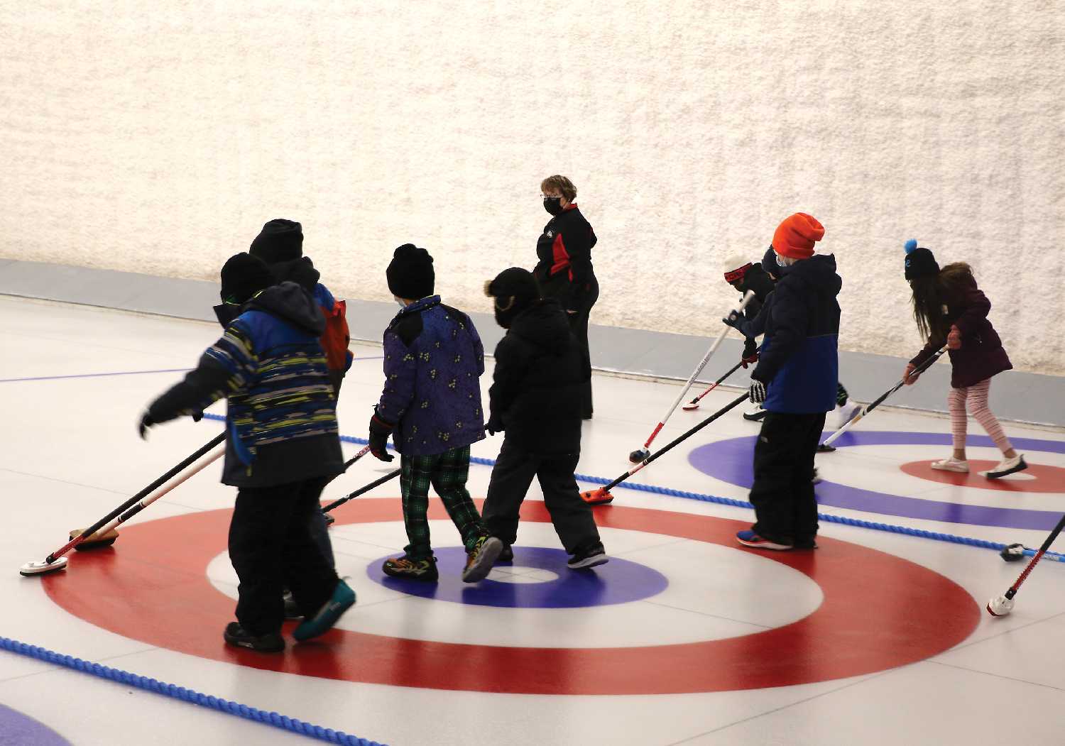 Children from grades three and four from Maryfield School learning how to balance on the ice with curling brooms, with curling instructor Janet Lemon.