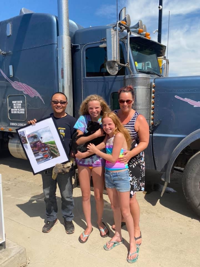 Trucker Jack Shao with the painting gifted to him by Chylisse Marchand, along with Marchand and her daughters Shay (holding Spooky) and Alli.