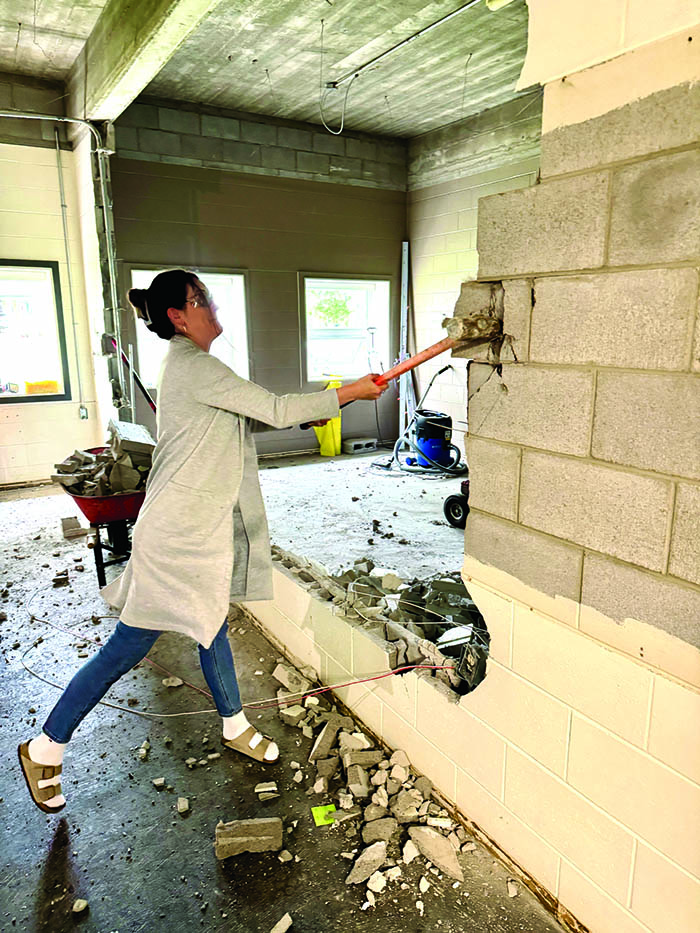 Home Ec teacher Laura Teale helps with demolition, sledgehammering a cindercrete wall, creating a more open space for the renovated Home Ec Lab.<br />