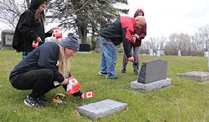 Young volunteers step forward to take over placing flags on graves of fallen veterans